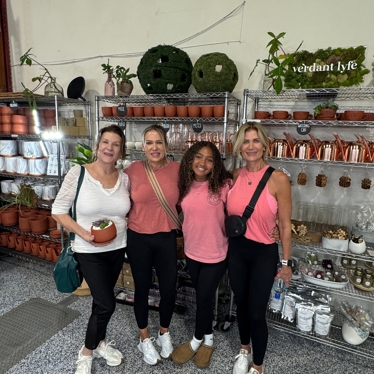 Four women posing for a photo in a store with plants and gardening supplies.