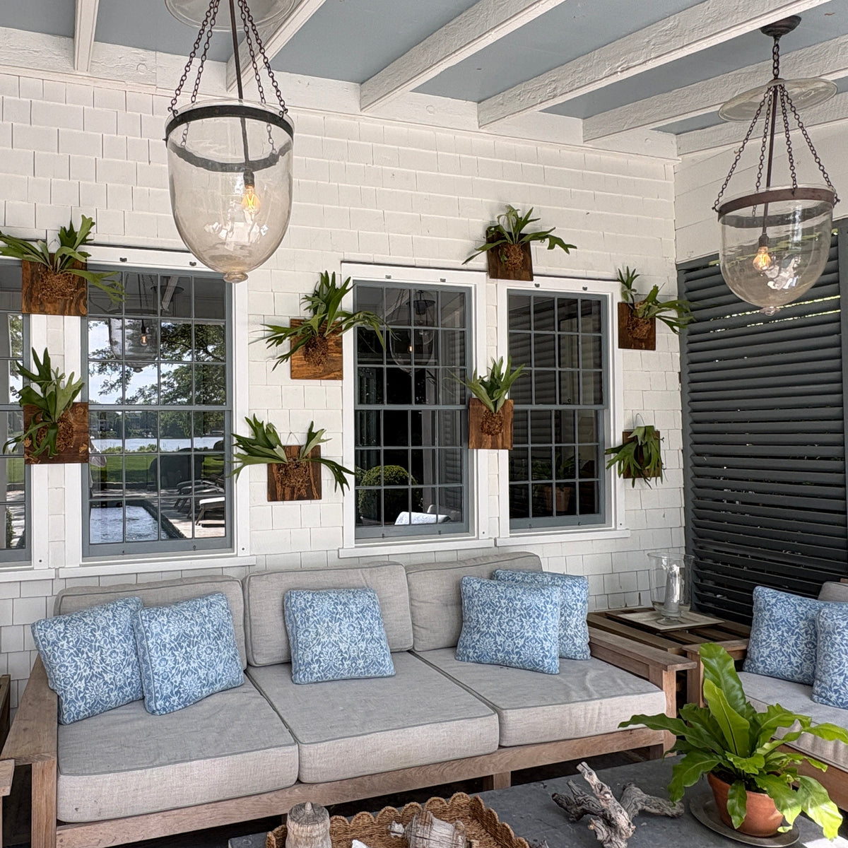 Outdoor patio with a sectional sofa, cushions, and potted plants on a sunny day.