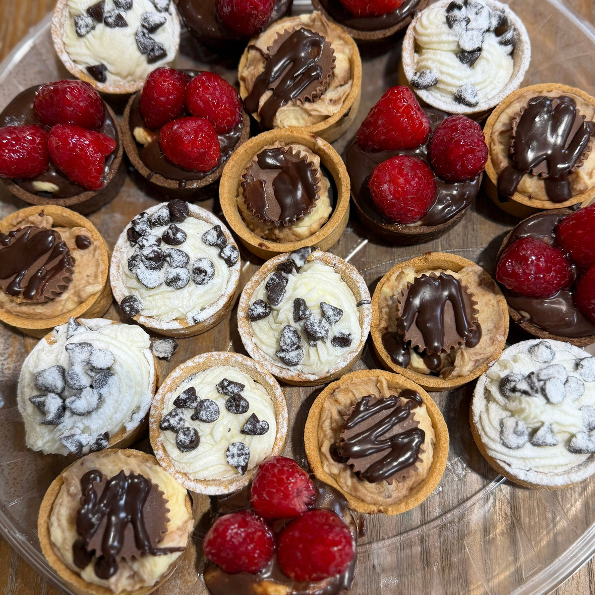 Assorted small desserts with berries on a clear plate