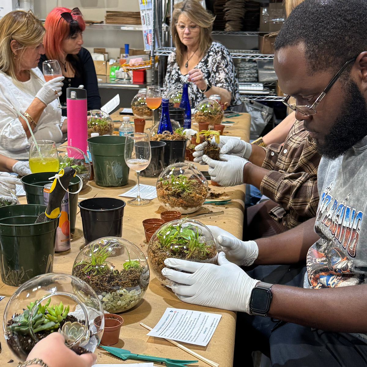 People working on terrariums at a table with various supplies