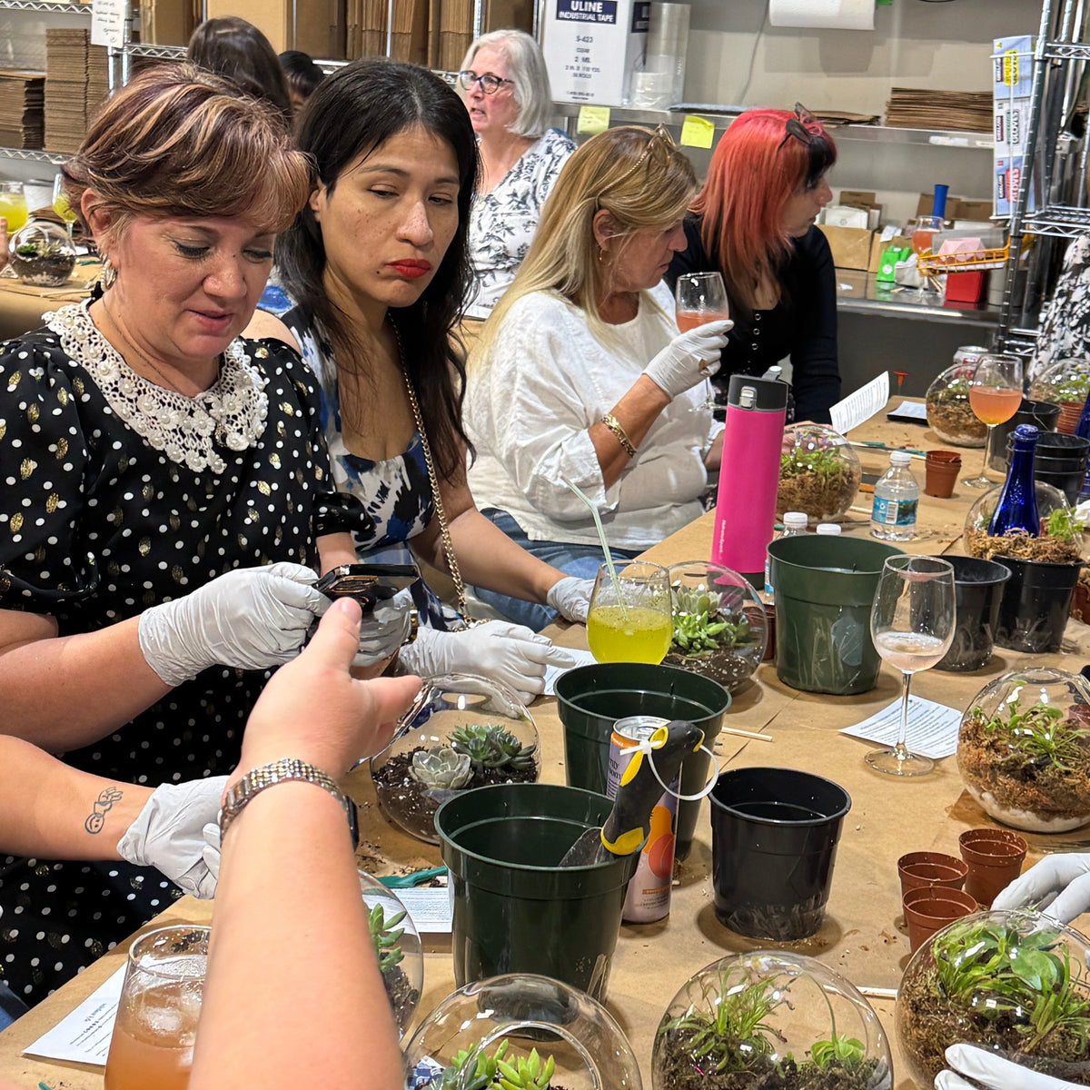People working on terrariums at a workshop with various materials and tools.
